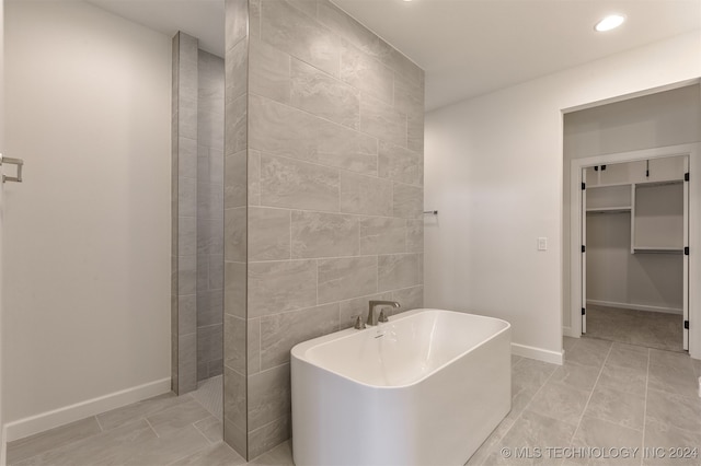 bathroom featuring a tub to relax in, tile walls, and tile patterned floors