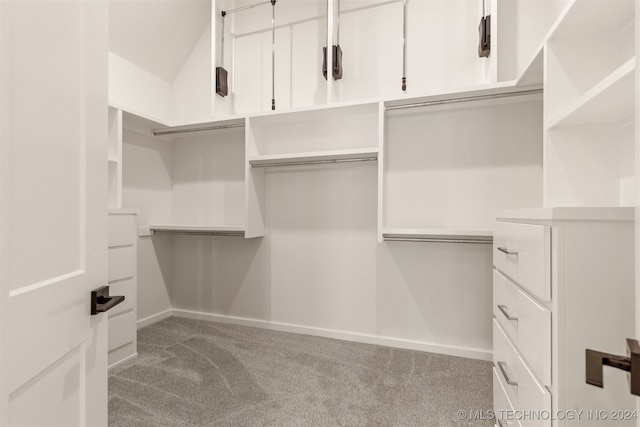 walk in closet featuring light carpet and vaulted ceiling