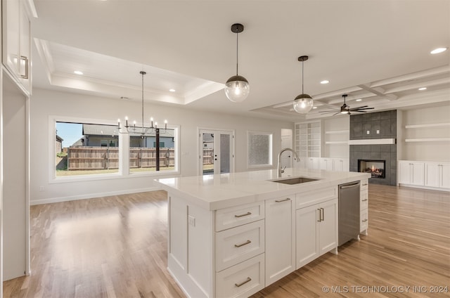 kitchen with a center island with sink, open floor plan, light wood-style floors, white cabinetry, and a sink