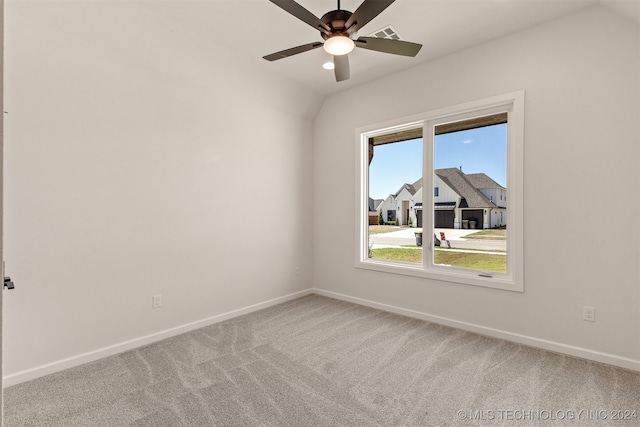 carpeted empty room featuring lofted ceiling, ceiling fan, a residential view, and baseboards