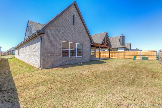 back of property featuring board and batten siding, brick siding, a lawn, and a fenced backyard