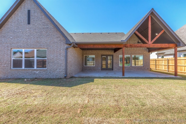 rear view of house featuring roof with shingles, brick siding, a lawn, a patio area, and fence