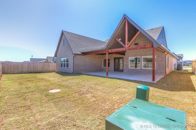 back of property with brick siding, a lawn, a patio area, and fence