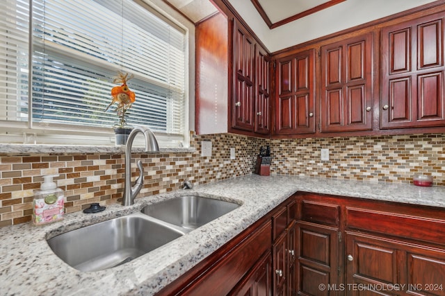 kitchen with ornamental molding, decorative backsplash, light stone countertops, and sink