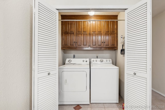 clothes washing area with washer and clothes dryer, light tile patterned floors, and cabinets