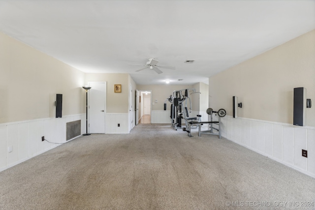 exercise room with light colored carpet and ceiling fan