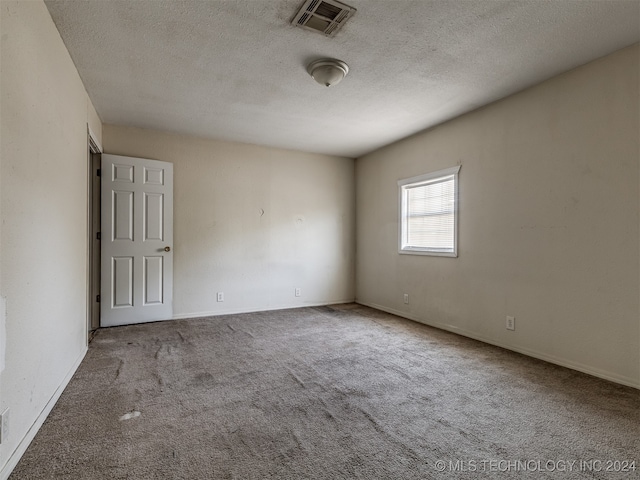 unfurnished room with a textured ceiling and light colored carpet