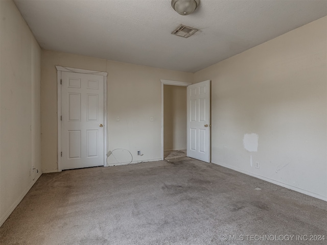 carpeted empty room featuring a textured ceiling