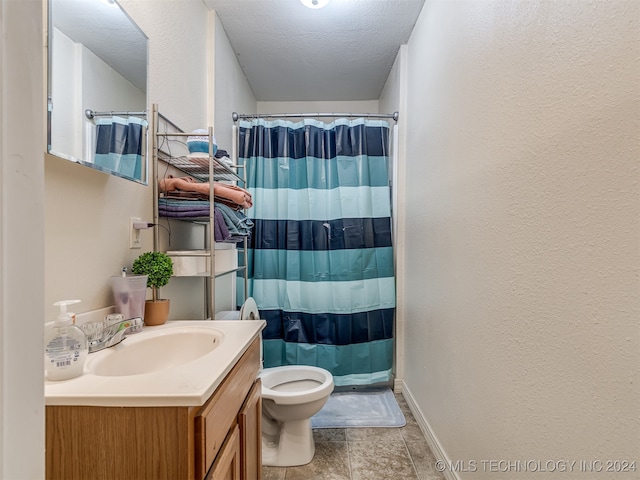 bathroom with a shower with curtain, vanity, tile patterned floors, toilet, and a textured ceiling