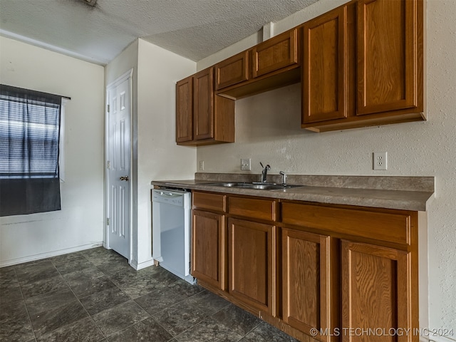 kitchen featuring white dishwasher, sink, and a textured ceiling