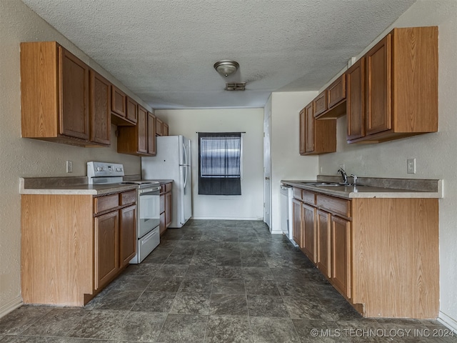 kitchen with white appliances, sink, and a textured ceiling