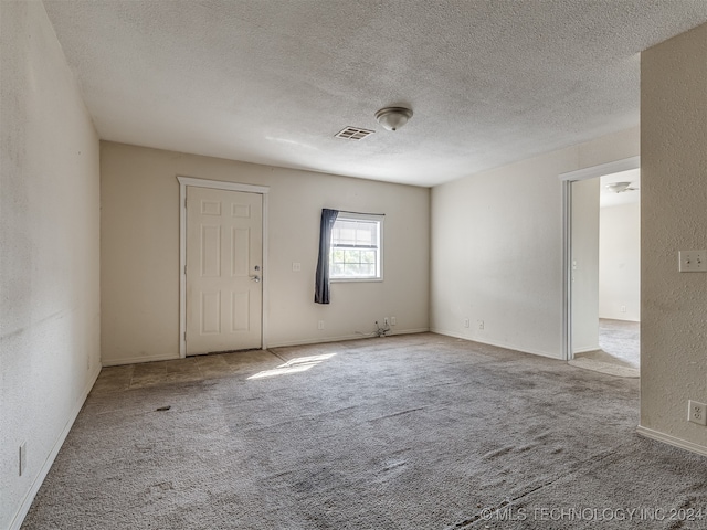 carpeted spare room with a textured ceiling