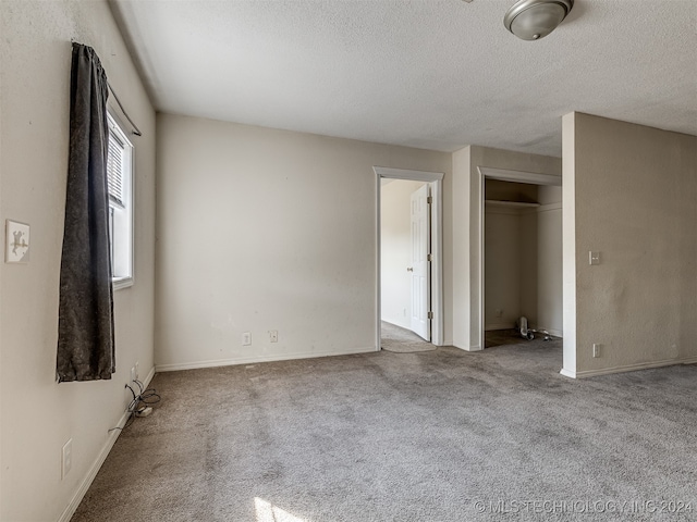 unfurnished bedroom featuring a closet, a textured ceiling, and light carpet