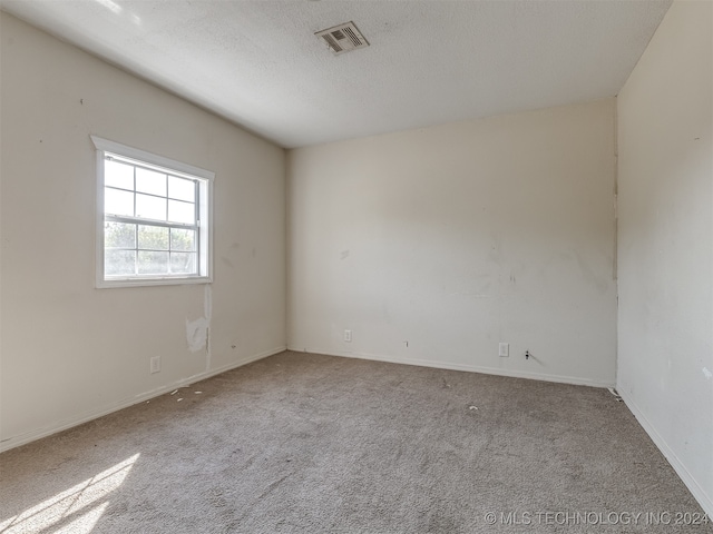 carpeted empty room with a textured ceiling