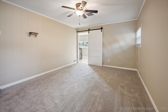 unfurnished room featuring ornamental molding, carpet floors, ceiling fan, and a barn door