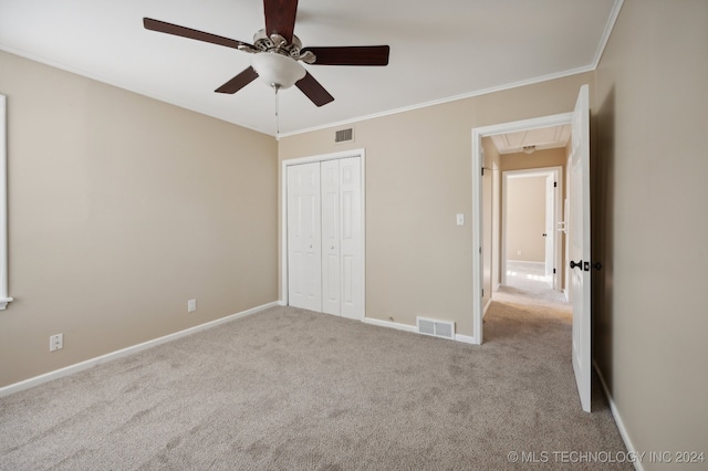 unfurnished bedroom featuring ceiling fan, light colored carpet, a closet, and ornamental molding