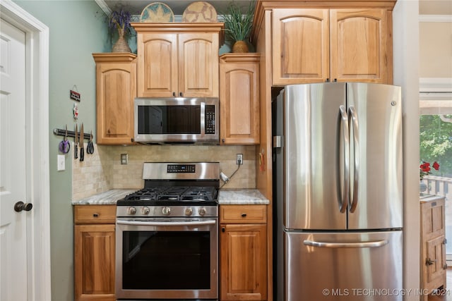 kitchen featuring backsplash, light stone countertops, stainless steel appliances, and ornamental molding