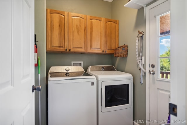 clothes washing area featuring washer and clothes dryer and cabinets