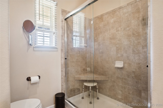 bathroom featuring toilet and a shower with shower door