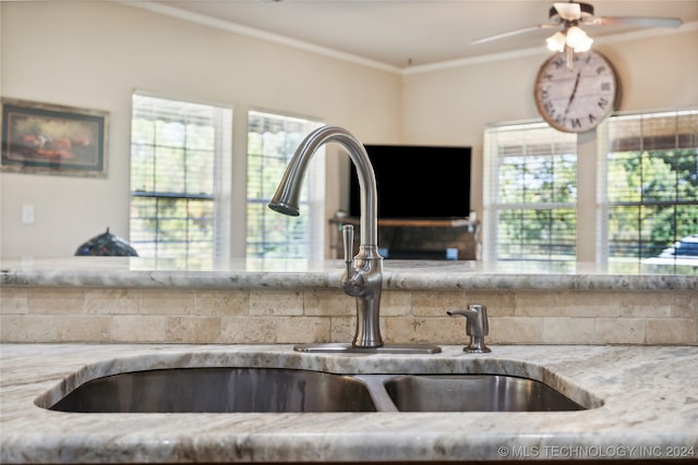 kitchen featuring light stone counters, a wealth of natural light, crown molding, and sink