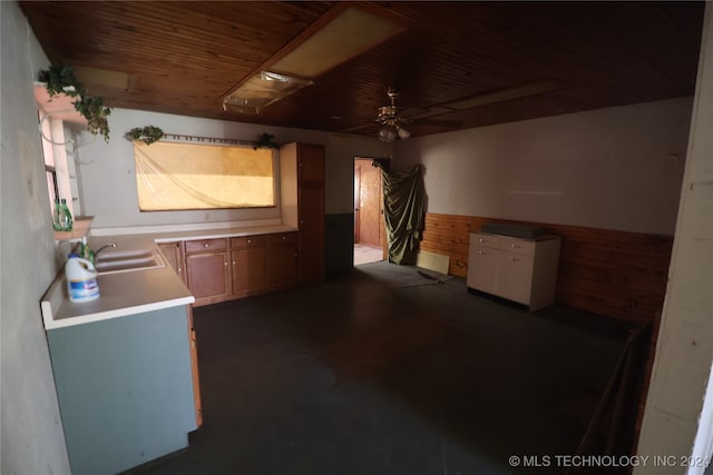 kitchen featuring wood walls, sink, and ceiling fan