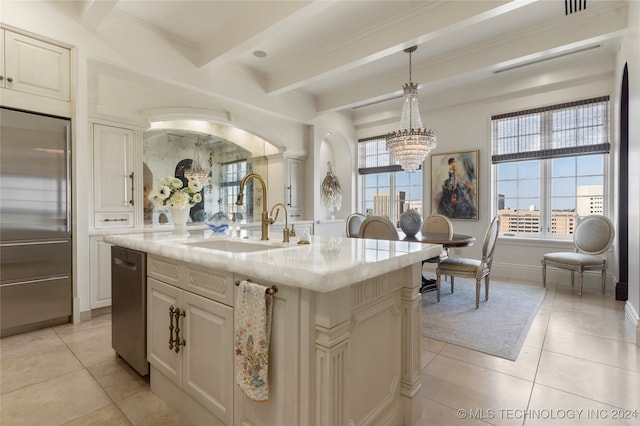 kitchen featuring a healthy amount of sunlight, sink, beamed ceiling, pendant lighting, and a center island with sink