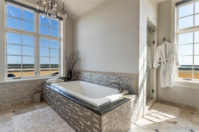 bathroom featuring a chandelier, separate shower and tub, vaulted ceiling, and plenty of natural light