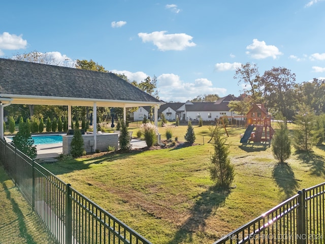 view of yard featuring a fenced in pool and a playground