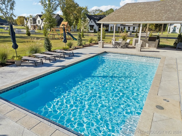 view of swimming pool featuring a yard, a patio area, and a playground