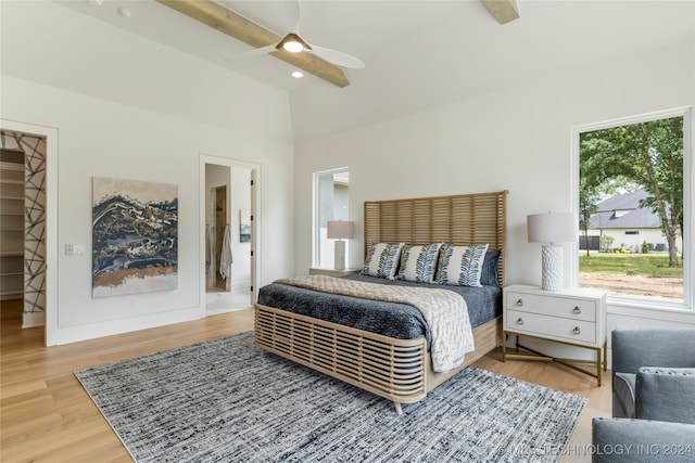 bedroom featuring connected bathroom, ceiling fan, hardwood / wood-style flooring, and vaulted ceiling with beams