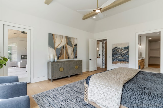 bedroom featuring ceiling fan, hardwood / wood-style flooring, vaulted ceiling with beams, and ensuite bath