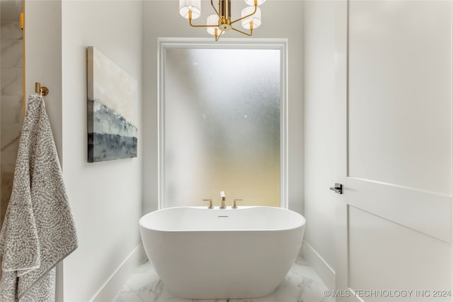 bathroom featuring a notable chandelier and a tub