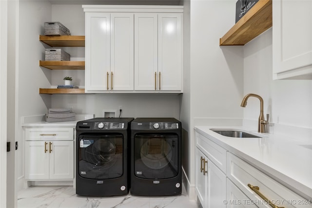 clothes washing area featuring cabinets, washer and dryer, and sink