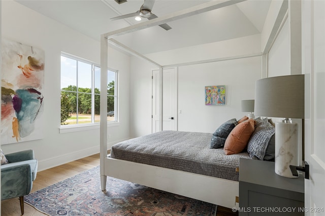 bedroom with ceiling fan, vaulted ceiling, and hardwood / wood-style floors