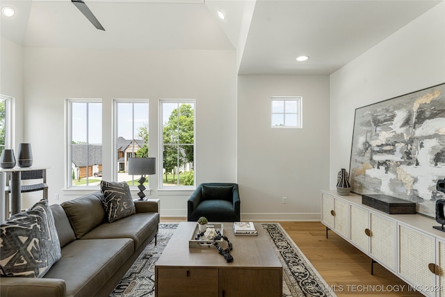 living room with light hardwood / wood-style floors, lofted ceiling, and ceiling fan