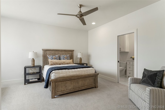 bedroom featuring ensuite bathroom, light colored carpet, and ceiling fan