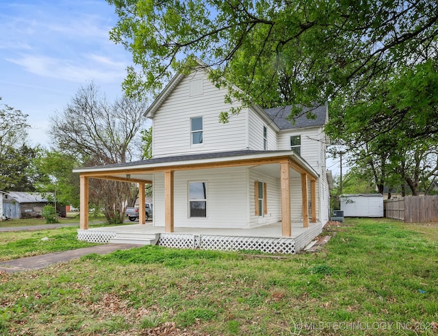 farmhouse with a porch, an outdoor structure, a front lawn, and central AC unit