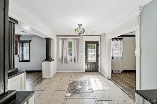 foyer with light hardwood / wood-style flooring, crown molding, and ornate columns