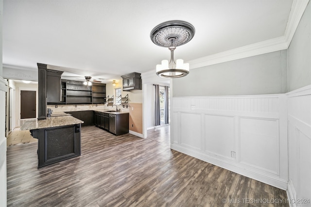 kitchen with light stone counters, ornamental molding, sink, decorative light fixtures, and dark hardwood / wood-style floors