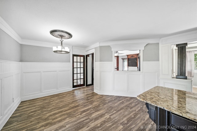 unfurnished dining area featuring ornamental molding, a notable chandelier, and dark hardwood / wood-style flooring