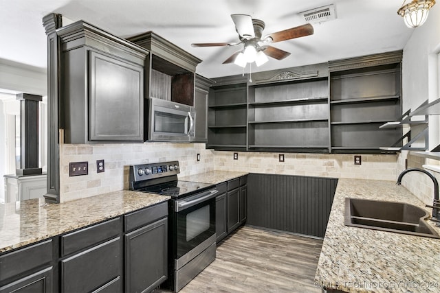 kitchen with light wood-type flooring, stainless steel appliances, tasteful backsplash, sink, and decorative columns