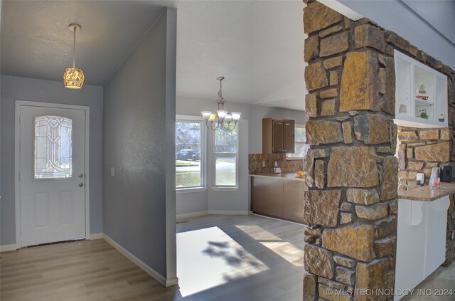 foyer entrance with lofted ceiling, a chandelier, and light wood-type flooring