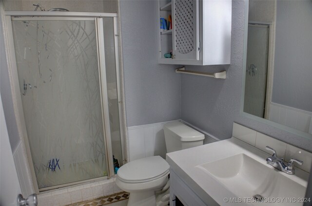 bathroom featuring vanity, a shower with shower door, and toilet