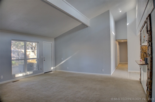 empty room featuring light colored carpet and vaulted ceiling with beams