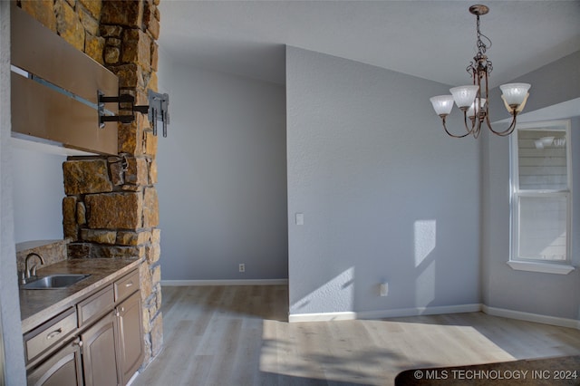 kitchen featuring a notable chandelier, decorative light fixtures, sink, and light hardwood / wood-style floors