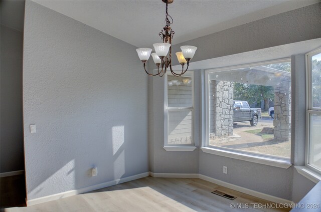 unfurnished dining area featuring a notable chandelier and light hardwood / wood-style flooring