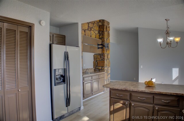 kitchen featuring dark brown cabinetry, sink, hanging light fixtures, light hardwood / wood-style flooring, and stainless steel fridge with ice dispenser