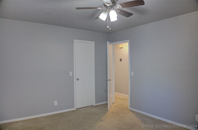 unfurnished room with light colored carpet and ceiling fan