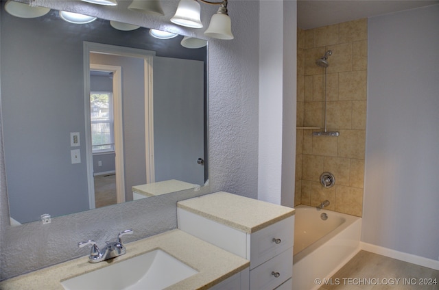 bathroom with tiled shower / bath combo and vanity