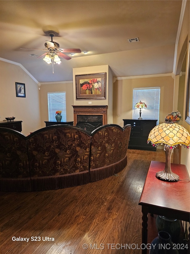 living room with dark wood-type flooring, ceiling fan, crown molding, and vaulted ceiling